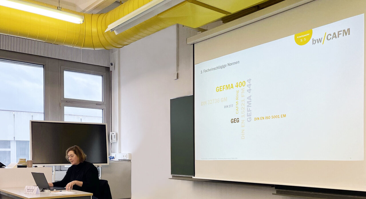 Projektleiterin "bwCAFM" vor einer Präsentationsleinwand.